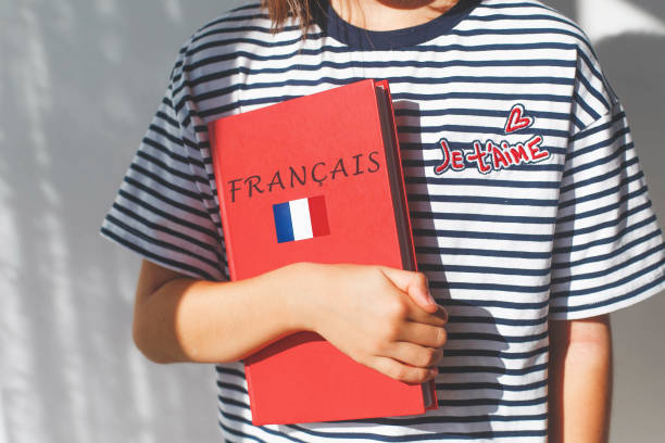 one white girl child schoolgirl with t-shirt with i love you in french and french textbook with french inscription and flag of France, foreign language learning concept.