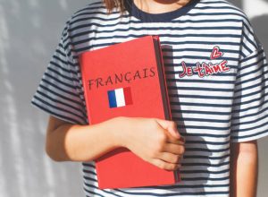 one white girl child schoolgirl with t-shirt with i love you in french and french textbook with french inscription and flag of France, foreign language learning concept.