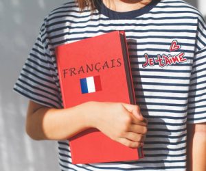 one white girl child schoolgirl with t-shirt with i love you in french and french textbook with french inscription and flag of France, foreign language learning concept.