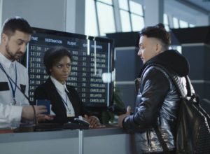 Men and women walking through counter with multiethnic employees in airport passing biometric and passport control.