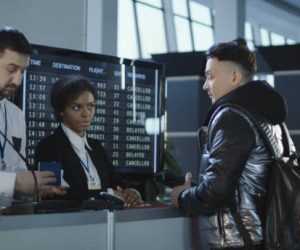 Men and women walking through counter with multiethnic employees in airport passing biometric and passport control.