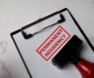 Red Handle Rubber Stamper and Permanent Residency text isolated on White Background.