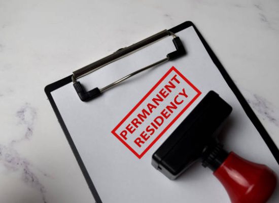 Red Handle Rubber Stamper and Permanent Residency text isolated on White Background.