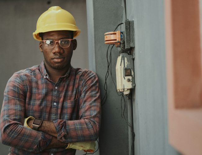 man in blue white and red plaid button up shirt wearing yellow hard hat holding black